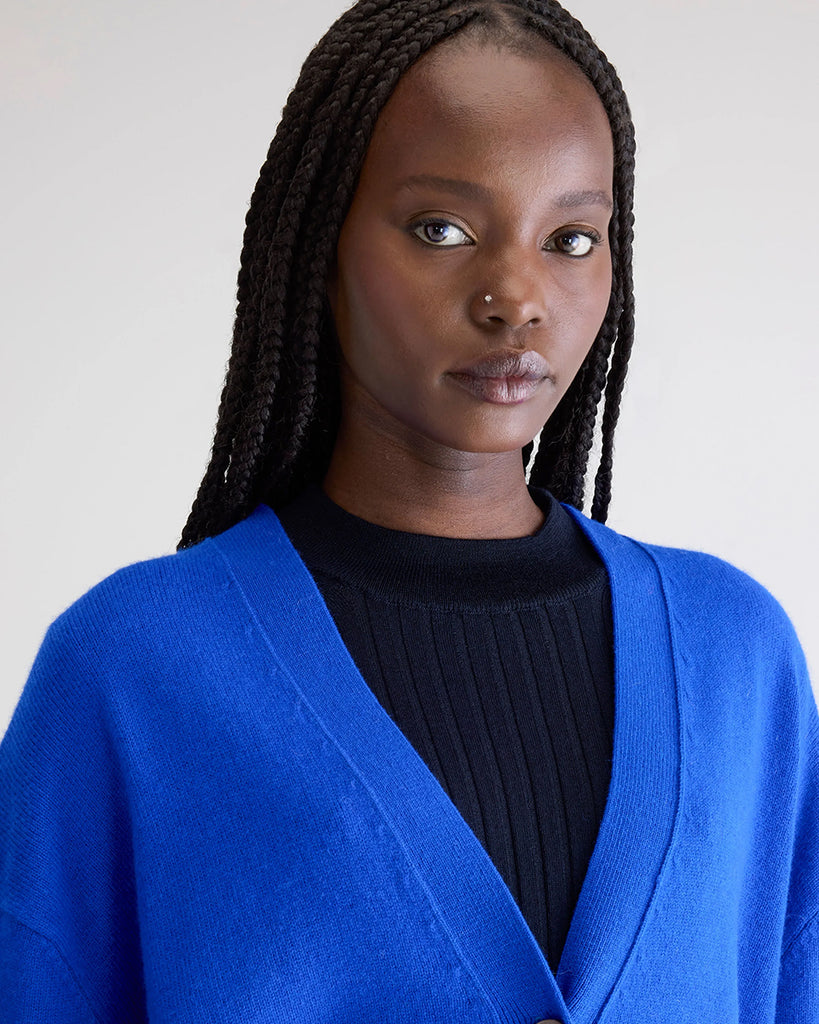 Oversizowy kardigan Gekkin Bellerose z opadającymi ramionami i luźnymi, długimi rękawami. Posiada dekolt w serek. Zapinany na guziki. Wykończony ściągaczami. Wykonany z miękkiej, naturalnej dzianiny z wełny i bawełny