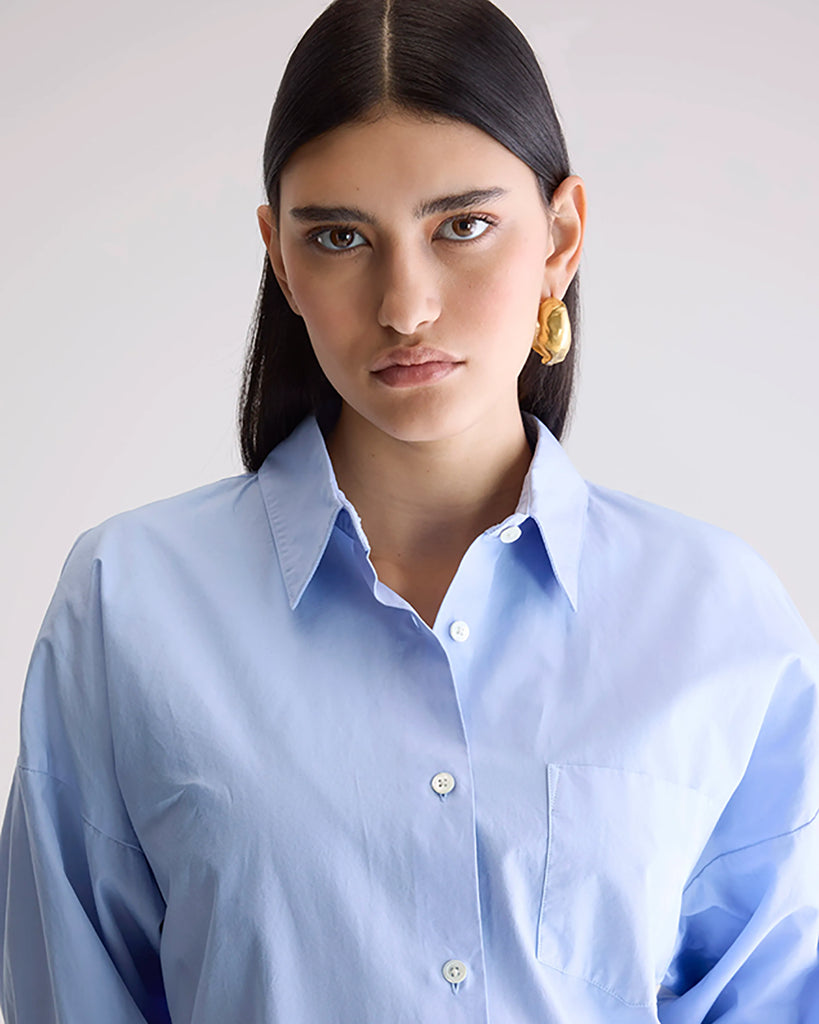 Klasyczna, oversizowa koszula w męskim stylu Giorgia Bellerose z kołnierzykiem, opadającymi ramionami i luźnymi rękawami zakończonymi mankietami. Zapinana na guziki. Posiada przednią kieszonkę na wysokości lewej piersi. Na plecach koszula ma zakładkę.