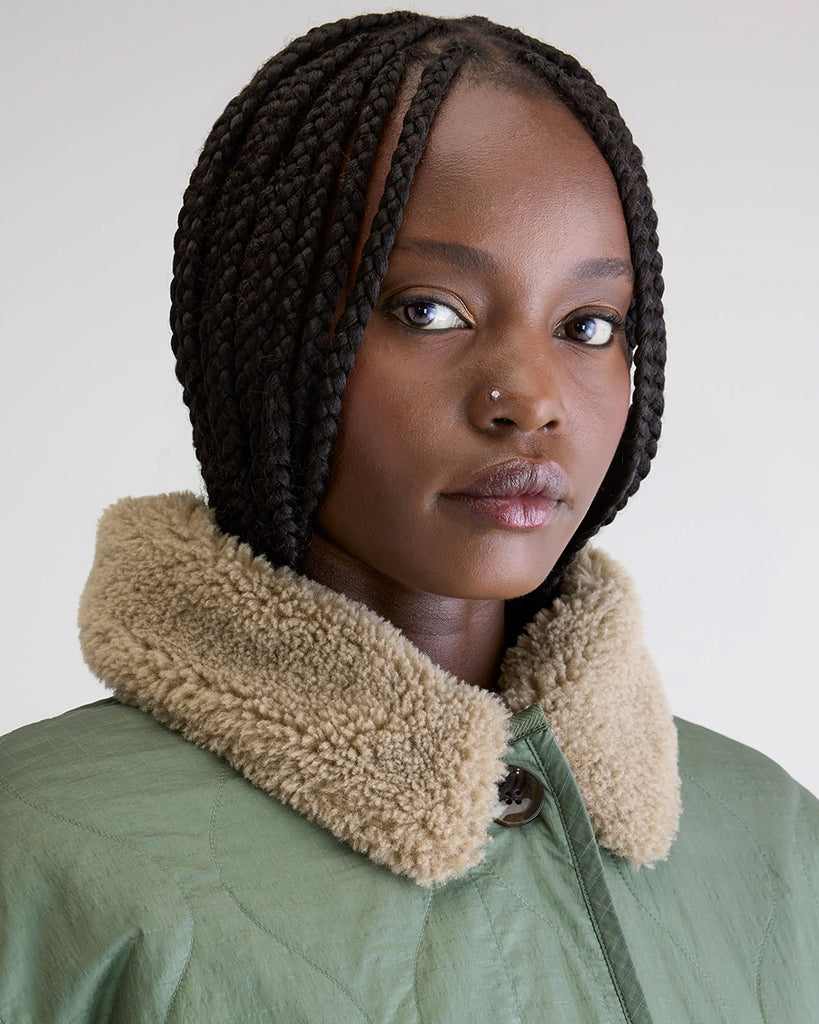 Oversizowa, dwustronna kurtka Hampton Bellerose w stylu worker. Posiada kołnierzyk i wywijane rękawy ze sztucznego kożucha. Z jednej strony wykonana ze śliskiej, pikowanej tkaniny w zielonym kolorze, z drugiej z patchworkowego materiału w różnych kolorach z elementami ze eko "misia"