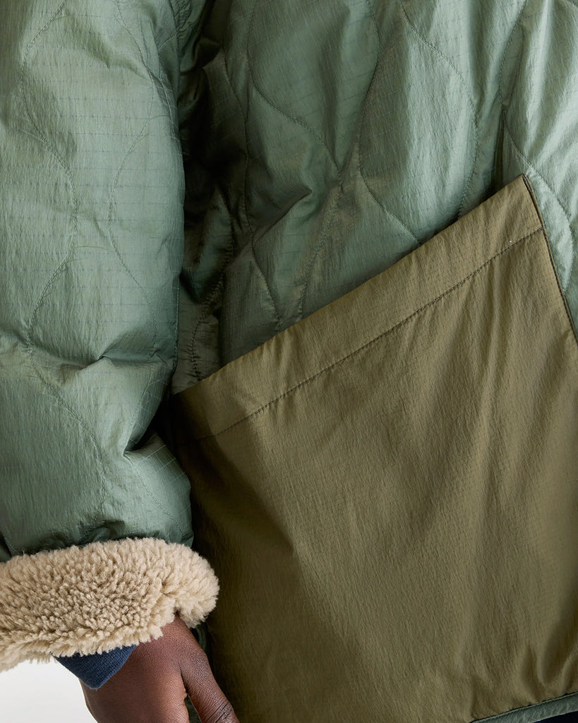 Oversizowa, dwustronna kurtka Hampton Bellerose w stylu worker. Posiada kołnierzyk i wywijane rękawy ze sztucznego kożucha. Z jednej strony wykonana ze śliskiej, pikowanej tkaniny w zielonym kolorze, z drugiej z patchworkowego materiału w różnych kolorach z elementami ze eko "misia"