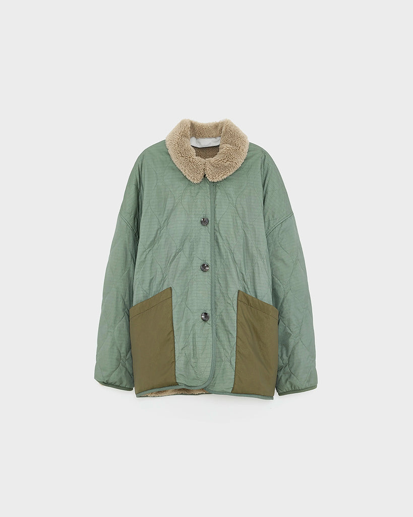 Oversizowa, dwustronna kurtka Hampton Bellerose w stylu worker. Posiada kołnierzyk i wywijane rękawy ze sztucznego kożucha. Z jednej strony wykonana ze śliskiej, pikowanej tkaniny w zielonym kolorze, z drugiej z patchworkowego materiału w różnych kolorach z elementami ze eko "misia"