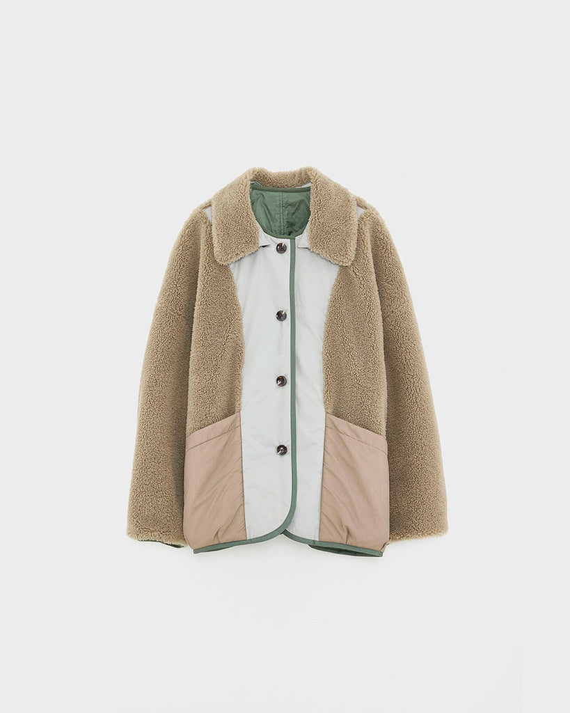 Oversizowa, dwustronna kurtka Hampton Bellerose w stylu worker. Posiada kołnierzyk i wywijane rękawy ze sztucznego kożucha. Z jednej strony wykonana ze śliskiej, pikowanej tkaniny w zielonym kolorze, z drugiej z patchworkowego materiału w różnych kolorach z elementami ze eko "misia"