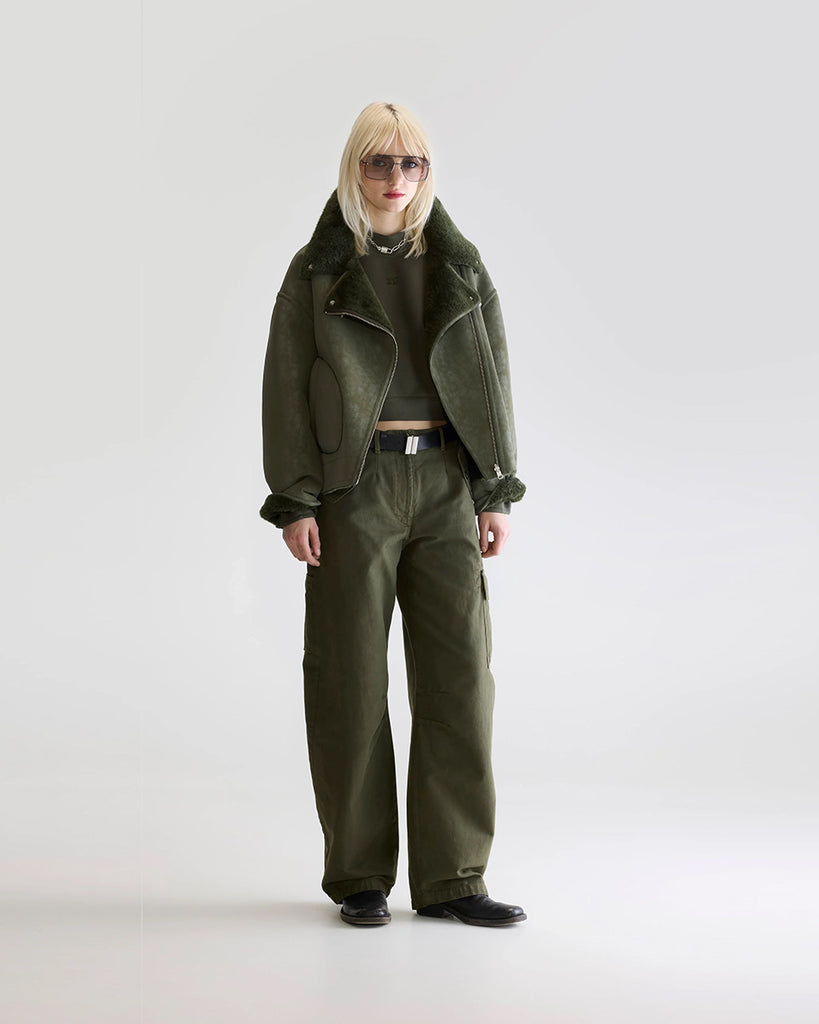 Dwustronna, zielona kurtka z ekologicznego kożucha o kroju ramoneski Hedwee Bellerose z dużym kołnierzem, opadającymi ramionami i wywijanymi rękawami. Z przodu posiada dwie, duże kieszenie. Zapinany na idący na skos zamek błyskawiczny. Z jednej strony wykonany z imitacji skóry, z drugiej ze sztucznego, miłego w dotyku "misia".