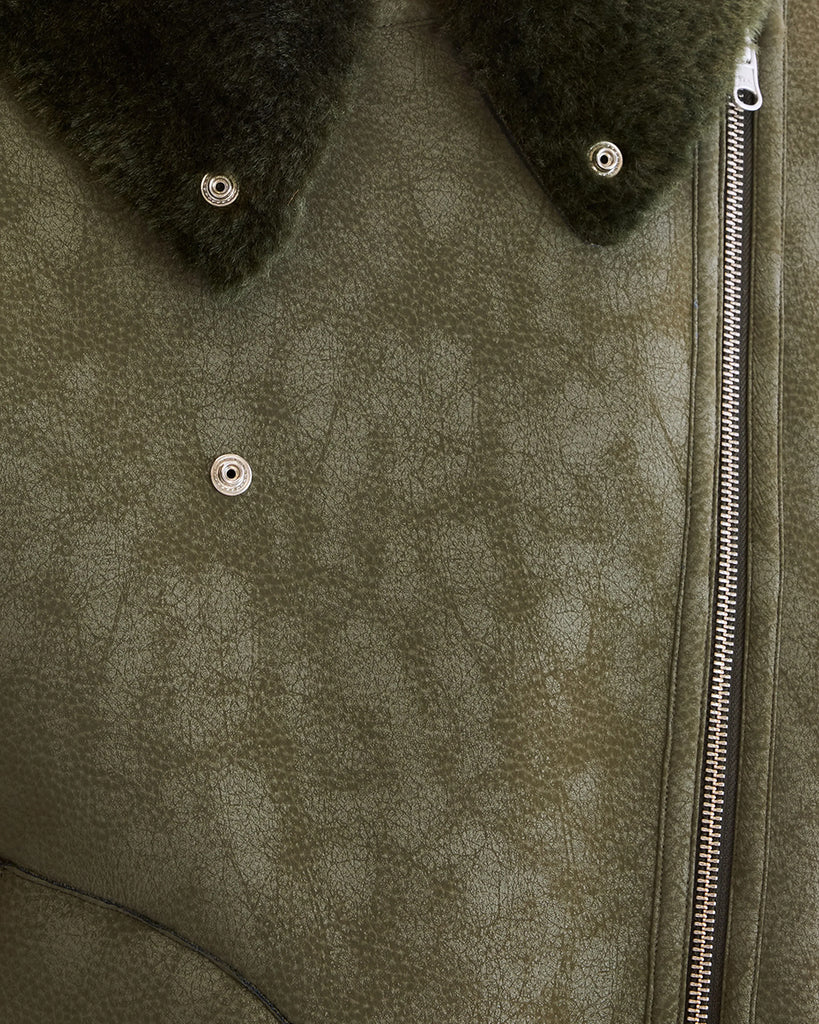 Dwustronna, zielona kurtka z ekologicznego kożucha o kroju ramoneski Hedwee Bellerose z dużym kołnierzem, opadającymi ramionami i wywijanymi rękawami. Z przodu posiada dwie, duże kieszenie. Zapinany na idący na skos zamek błyskawiczny. Z jednej strony wykonany z imitacji skóry, z drugiej ze sztucznego, miłego w dotyku "misia".