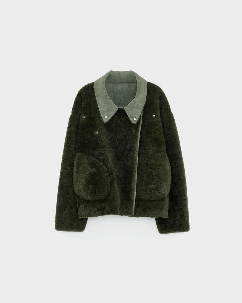 Dwustronna, zielona kurtka z ekologicznego kożucha o kroju ramoneski Hedwee Bellerose z dużym kołnierzem, opadającymi ramionami i wywijanymi rękawami. Z przodu posiada dwie, duże kieszenie. Zapinany na idący na skos zamek błyskawiczny. Z jednej strony wykonany z imitacji skóry, z drugiej ze sztucznego, miłego w dotyku "misia".