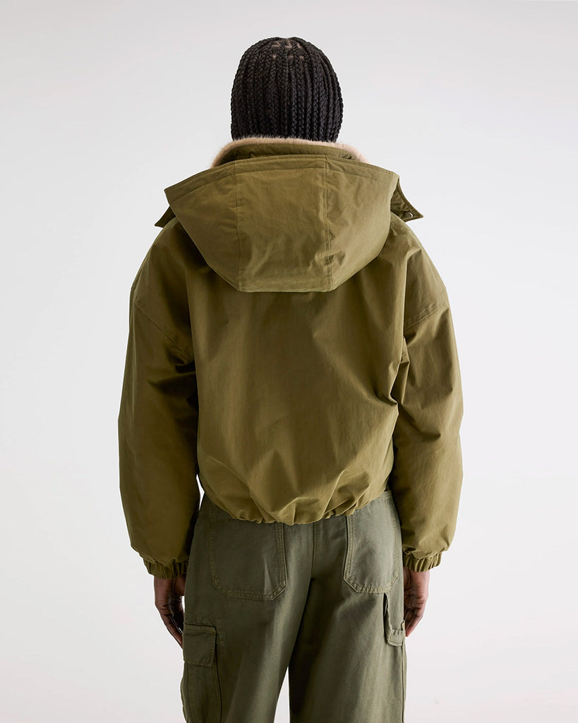 Krótka, ocieplana kurtka Herna Bellerose z kapturem i ciepłą podpinką ze sztucznego futra w kontrastowym kolorze. Kurtka ma opadające ramiona i szerokie rękawy zakończone elastycznym ściągaczem.