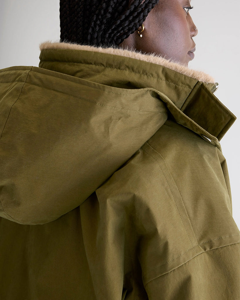 Krótka, ocieplana kurtka Herna Bellerose z kapturem i ciepłą podpinką ze sztucznego futra w kontrastowym kolorze. Kurtka ma opadające ramiona i szerokie rękawy zakończone elastycznym ściągaczem.