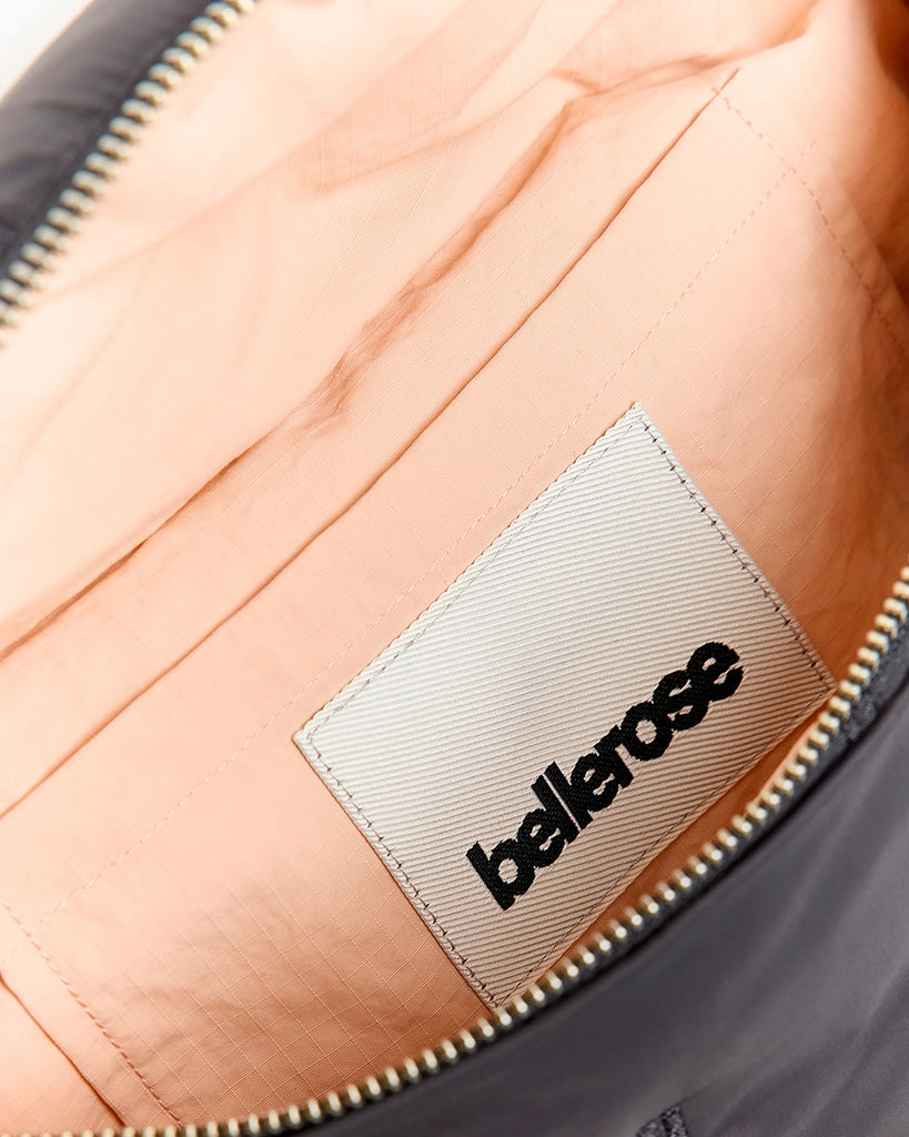 Pikowana, niewielka torebka-nerka Hosie Bellerose z miękkiej, "puchowej" tkaniny. Zapinana na zamek błyskawiczny. Wewnątrz obszyta kontrastową podszewką. Torebka ma szeroki, pleciony pasek o regulowanej długości do wygodnego przewieszenia przez ramię.