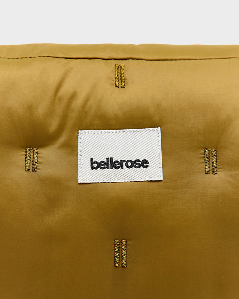 Pikowana, niewielka torebka-nerka Hosie Bellerose z miękkiej, "puchowej" tkaniny. Zapinana na zamek błyskawiczny. Wewnątrz obszyta kontrastową podszewką. Torebka ma szeroki, pleciony pasek o regulowanej długości do wygodnego przewieszenia przez ramię.