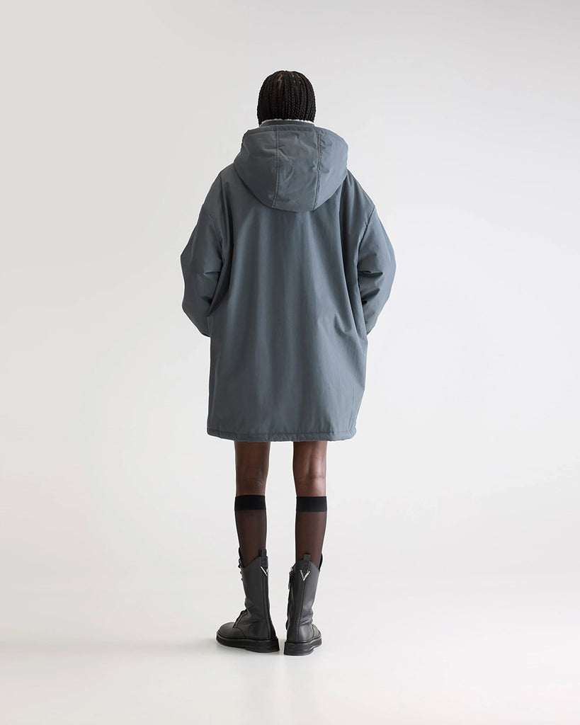 Długa, oversizowa parka Jade Bellerose z kapturem i ciepłą podpinką ze sztucznego futra w kontrastowym kolorze. Kurtka ma opadające ramiona i szerokie rękawy zakończone elastycznym ściągaczem. Posiada dwie, boczne kieszenie. 