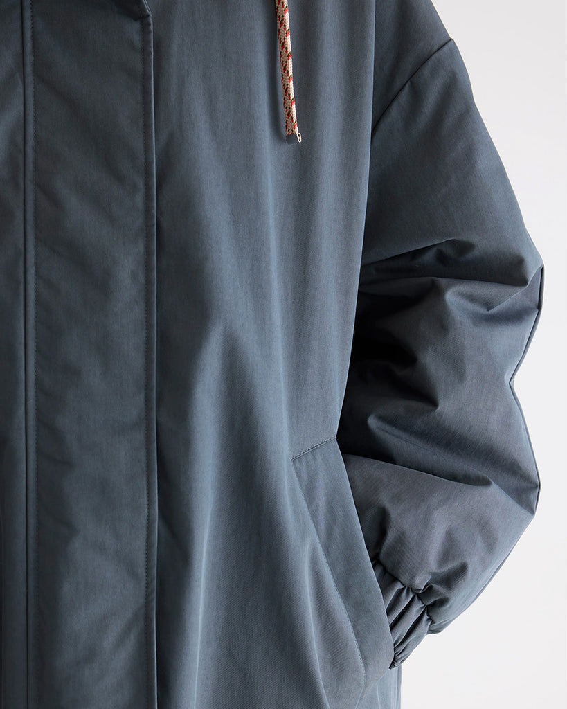 Długa, oversizowa parka Jade Bellerose z kapturem i ciepłą podpinką ze sztucznego futra w kontrastowym kolorze. Kurtka ma opadające ramiona i szerokie rękawy zakończone elastycznym ściągaczem. Posiada dwie, boczne kieszenie. 