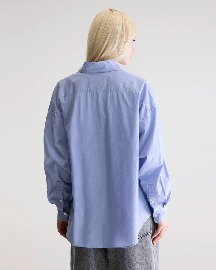 Niebieska, oversizowa koszula w cienkie prążki Gillian Bellerose z opadającymi ramionami i szerokimi rękawami zakończonymi wąskimi mankietami. Zapinana na guziki. Posiada bardzo ciekawą opcję asymetrycznego zapięcia i zwężenia w talii.