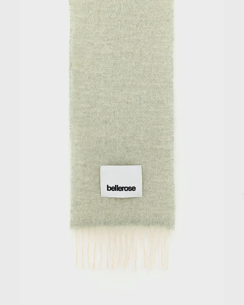 Ciepły, duży, zielony szalik Myllem Bellerose z kontrastowymi frędzlami. Posiada dużą naszywkę z logo marki. Wykonany z miękkiej dzianiny z wełną i moherem.