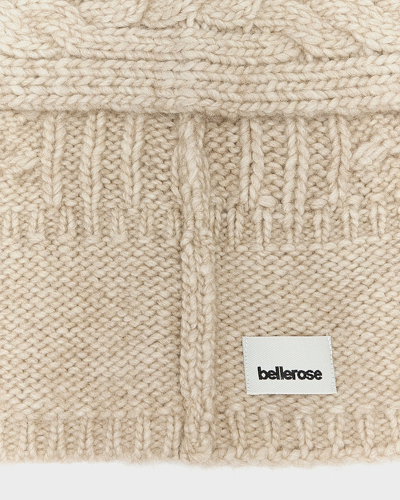 Dzianinowy, ciepły kapturek w stylu balaclavy Nan Bellerose z plecionym, warkoczowym wzorem. Wiązana pod szyją za pomocą szalika. Wykonana z dzianiny z wełną i alpaką.