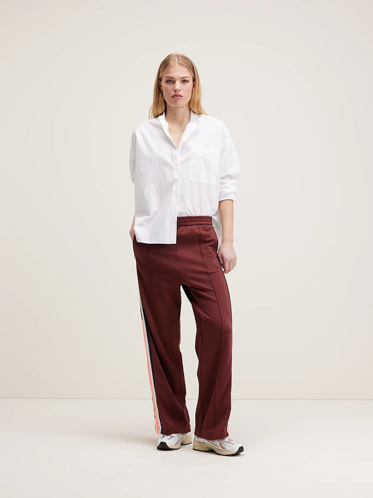 Luźne, brązowe spodnie dresowe Tania Bellerose z lampasami po bokach. Spodnie mają wysoki stan i prostą, luźną nogawkę.