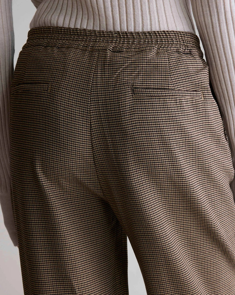 Luźne, materiałowe spodnie w drobną kratkę Tilla Bellerose ze średnim stanem z prostą, długą nogawką. Z tyłu elastyczne w pasie. Z przodu zapinane na guzik umieszczony z boku i zamek błyskawiczny. Spodnie mają dwie, boczne kieszenie i dwie tylne.