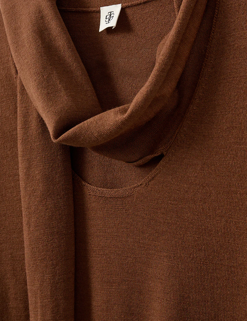 Cienki, brązowy sweter Bergen Scarf Cinnamon o dopasowanym kroju, z elastycznym ściagaczem w pasie i przy zakończeniach rękawów. Rękawy są długości do łokcia. Dekolt jest w nieco głębszy i okrągły z doszytym długim szalem, który można puścić luźno lub dowolnie związać. Wykonany w 100% z wełny merino.