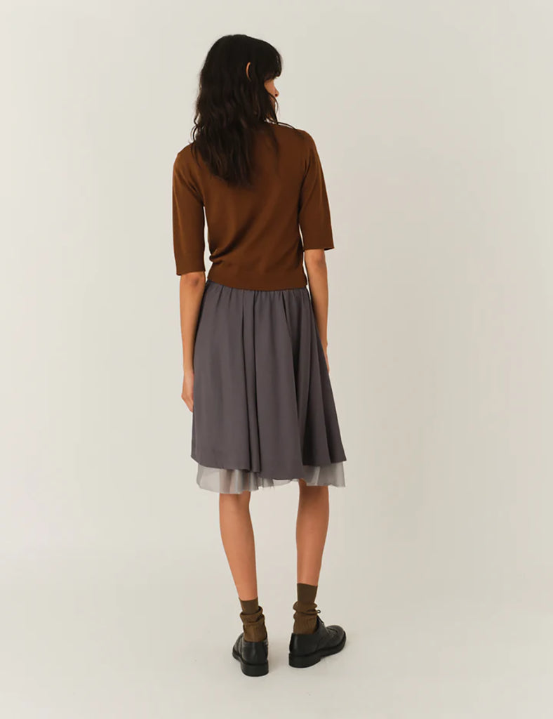 Cienki, brązowy sweter Bergen Scarf Cinnamon o dopasowanym kroju, z elastycznym ściagaczem w pasie i przy zakończeniach rękawów. Rękawy są długości do łokcia. Dekolt jest w nieco głębszy i okrągły z doszytym długim szalem, który można puścić luźno lub dowolnie związać. Wykonany w 100% z wełny merino.