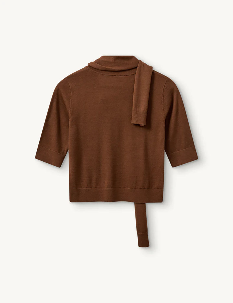 Cienki, brązowy sweter Bergen Scarf Cinnamon o dopasowanym kroju, z elastycznym ściagaczem w pasie i przy zakończeniach rękawów. Rękawy są długości do łokcia. Dekolt jest w nieco głębszy i okrągły z doszytym długim szalem, który można puścić luźno lub dowolnie związać. Wykonany w 100% z wełny merino.