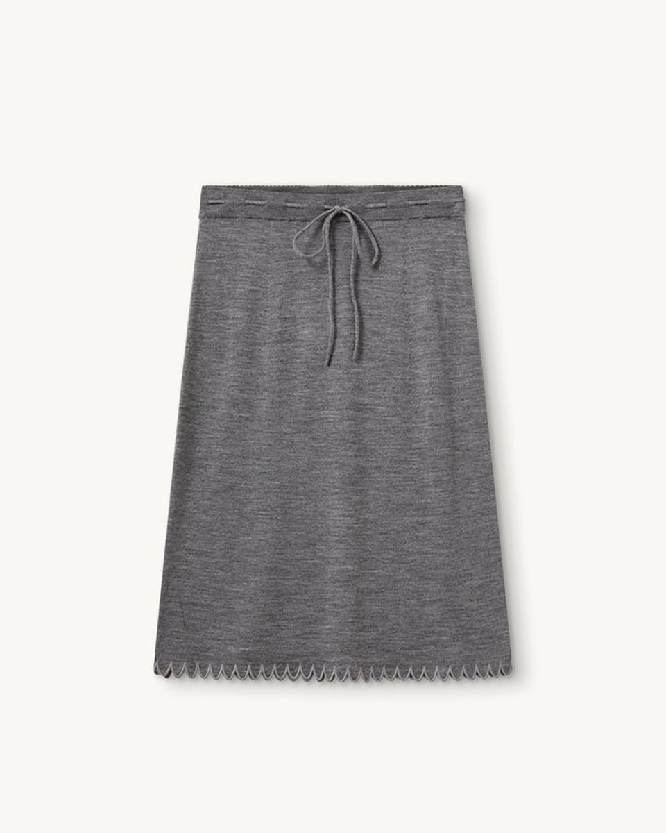 Dzianinowa, prosta spódnica Bergen Scallop Grey Melange z gładkim, elastycznym pasem. Wykonana z materiału o średniej grubości i gładkiej fakturze, który zachowuje swój kształt, a jednocześnie naturalnie się układa. Wiązanie z przodu oraz koronkowe wykończenie dołu nadają jej subtelny, dekoracyjny charakter. Wykonana z wełny merino.

-Dzianinowy model o prostym kroju

-100% wełna merino