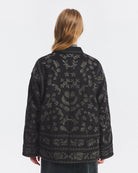 Luźna, lekko pudełkowa kurtka Bertille Antik Batik Black z mieszanki wełny, w całości ozdobiona haftem z kwiatowym motywem. Posiada dwie kieszenie z przodu. Zamek błyskawiczny wyróżniono ozdobnymi plecionkami, które nadają całości charakter boho. Charakterystycznym elementem są ozdobne, tradycyjne chińskie węzełki służące jako zapięcie. Model ten łączy w sobie inspirację tradycyjnymi ubiorami azjatyckimi z nowoczesną, miejską elegancją.