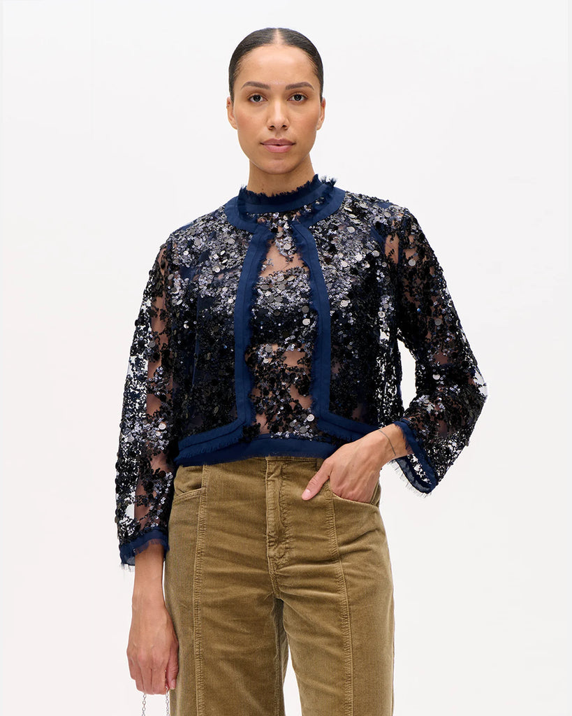 Cienka, transparentna kurtka Bethina Baum und Pferdgarten obszyta błyszczącymi cekinami. Wykończona delikatnymi frędzlami. Kurtka jest zapinana na haftki. Posiada prostu krój. Idealna do spodni i spódnic z wysokim stanem. Świetnie sprawdzi się w warstwowych stylizacjach.&nbsp;