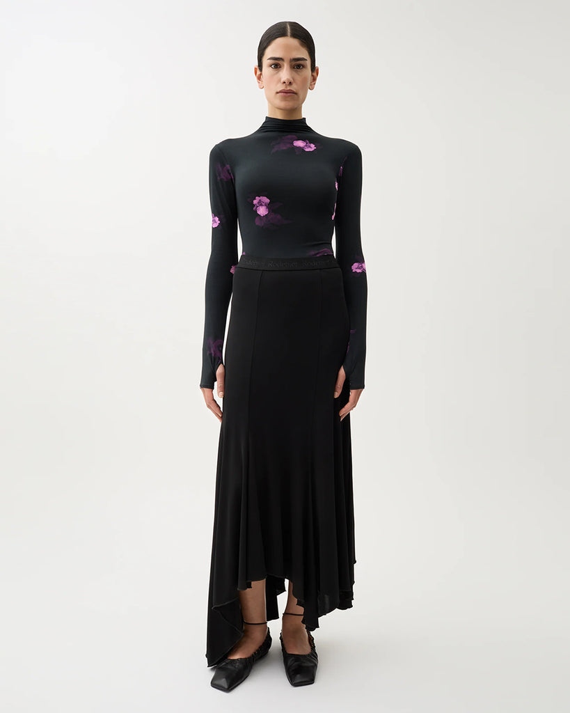 Czarne, przylegające Body Blake Bouquet Dark Purple w kwiatowy print z odkrytymi plecami i półgolfem zapinanym na guziki. Ma długie rękawy z otworami na kciuki. Wykonane z elastycznej bawełny. Świetnie sprawdzi się do eleganckich, wieczorowych stylizacji.