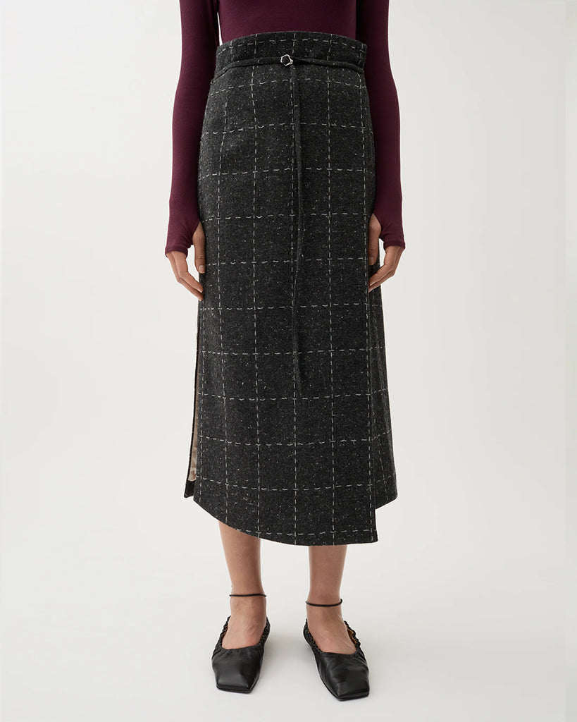 Spódnica midi Blanket Grey Melange w kolorze szarym w kratę. Ma wysoki stan oraz talię w stylu paperbag, którą zdobi sznurek z małą klamrą. Na bokach posiada rozcięcia. Wykonana z mieszanki wełny. Idealnie sprawdzi się do zwiewnych bluzek oraz marynarki Zola Check tej samej marki.&nbsp;
