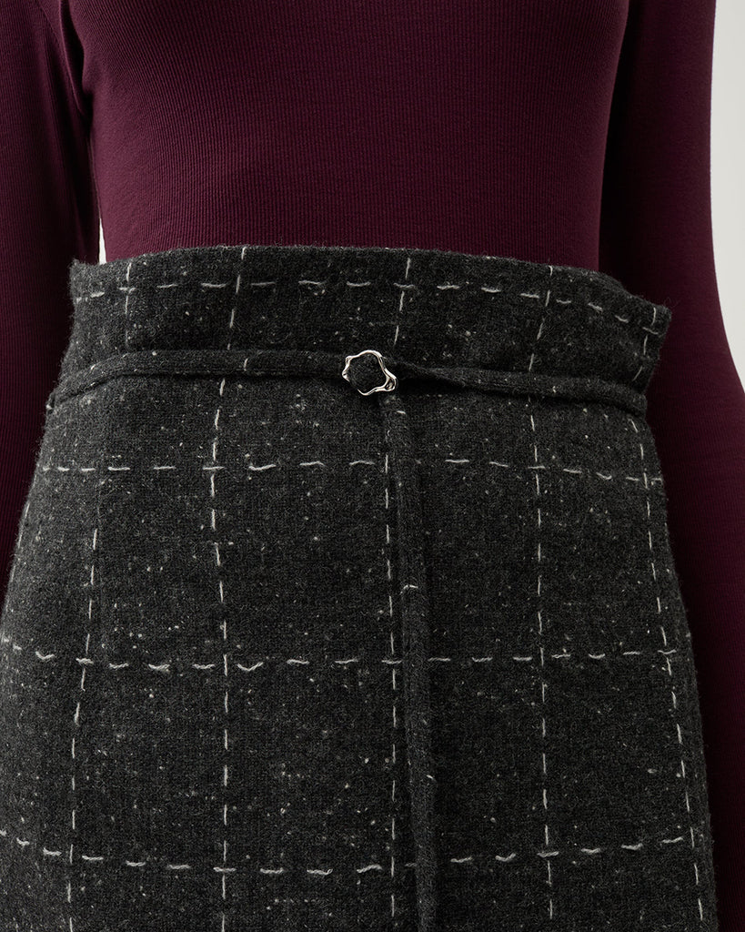 Spódnica midi Blanket Grey Melange w kolorze szarym w kratę. Ma wysoki stan oraz talię w stylu paperbag, którą zdobi sznurek z małą klamrą. Na bokach posiada rozcięcia. Wykonana z mieszanki wełny. Idealnie sprawdzi się do zwiewnych bluzek oraz marynarki Zola Check tej samej marki.&nbsp;
