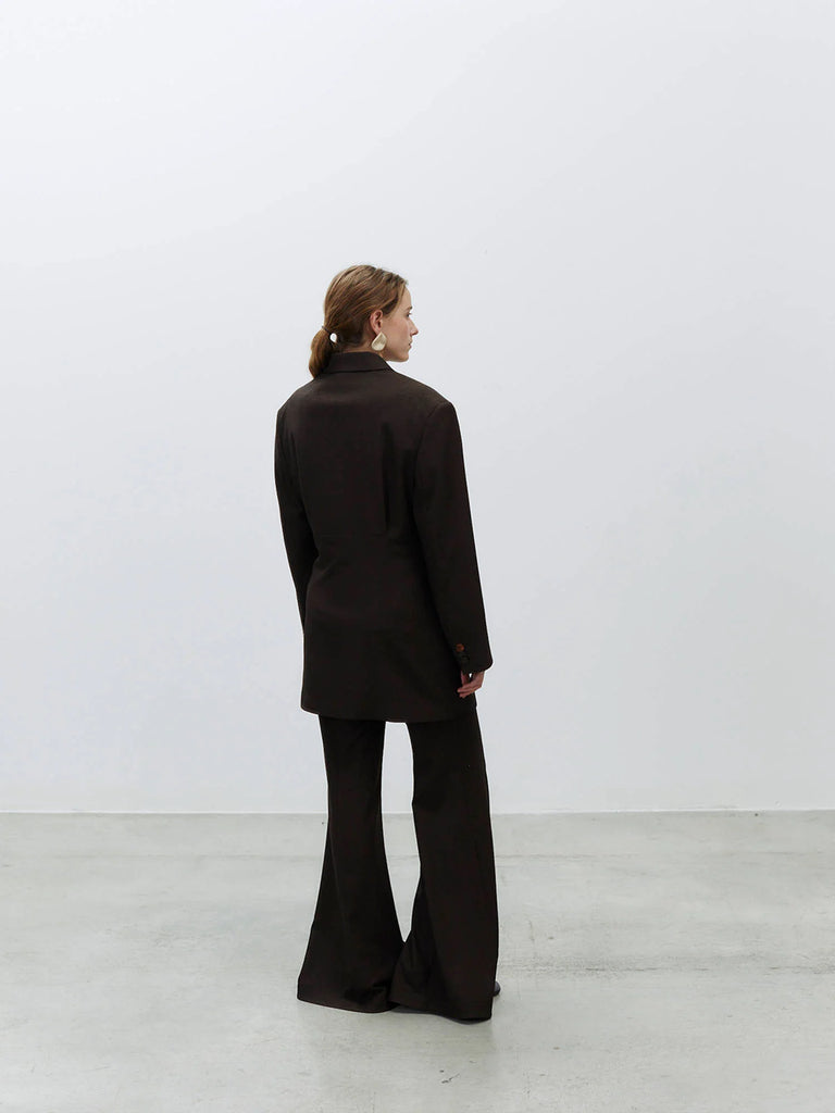 Bardzo długa, jednorzędowa marynarka Oversized Flannel Choco z wyraźnie zaznaczonymi ramionami i zwężeniem w talii. Ma asymetryczne zapięcie na guzik oraz kieszenie wpuszczane z przodu. Wykonana z mieszanki wełny i wiskozy.&nbsp;