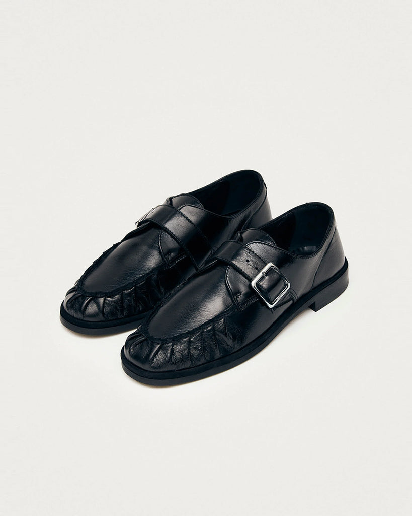 Czarne mokasyny Alohas Brandy Black Leather Loafers ze srebrną klamrą, która dodaje elegancji. Model charakteryzuje się unikatowym, marszczonym wykończeniem na nosku. Wykonane z wysokiej jakości skóry. Idealnie łączą ponadczasowy design z nowoczesnymi detalami.
