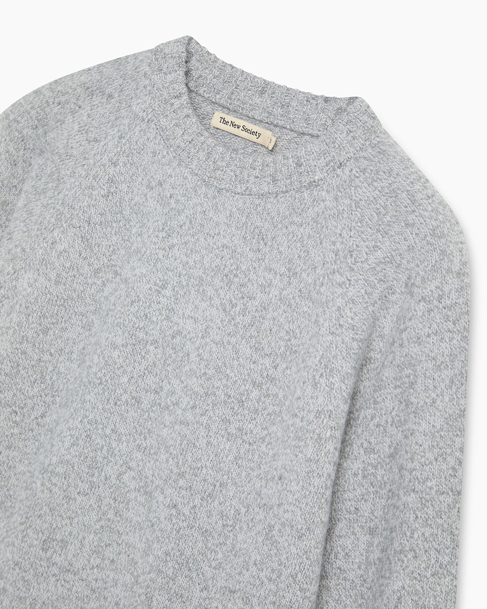 Jasny, szary sweter Breeze TNS Light Grey Melange o klasycznym, prostym kroju z okrągłym dekoltem wykończonym delikatnym ściągaczem. Posiada długie, nieco luźniejsze rękawy, które przy nadgarstkach przechodzą w szerokie ściągacze. Dół ma nieco krótszą długość, sięgającą do okolic pasa, co sprawia, że świetnie komponuje się z ciemnymi, szerokimi spodniami z wysokim stanem. Wykonany z mieszanki wełny merino i kaszmiru.

-Okrągły dekolt

-Wykończony ściągaczami&nbsp;

-Miękka tkanina z wełną merino i kaszmirem