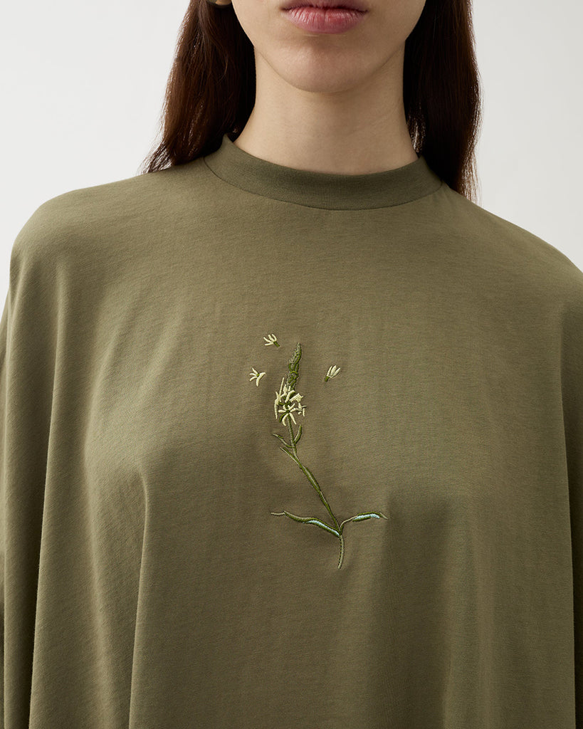 Oversizowy, lejący top Brick Kalamata Green z okrągłym dekoltem, opadającymi ramionami i luźnymi rękawami 3/4. Z przodu wyhaftowany jest kwiat. U dołu wykończony asymetrycznie. Wykonany z miękkiej bawełny organicznej.&nbsp;