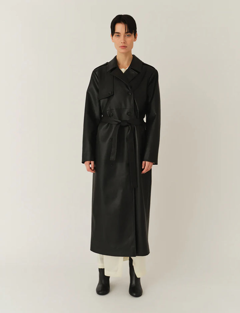 Długi, elegancki, dwurzędowy płaszcz Brooklyn Trench Black z klasycznymi detalami, wiązany w talii za pomocą wyciąganego, szerokiego paska. Posiada kołnierzyk, pagony na ramionach i luźne rękawy. Z tyłu u dołu ma rozcięcie. Płaszcz posiada dwie, boczne kieszenie. Jest zapinany na guziki. Wykończony w matowym, czarnym kolorze.