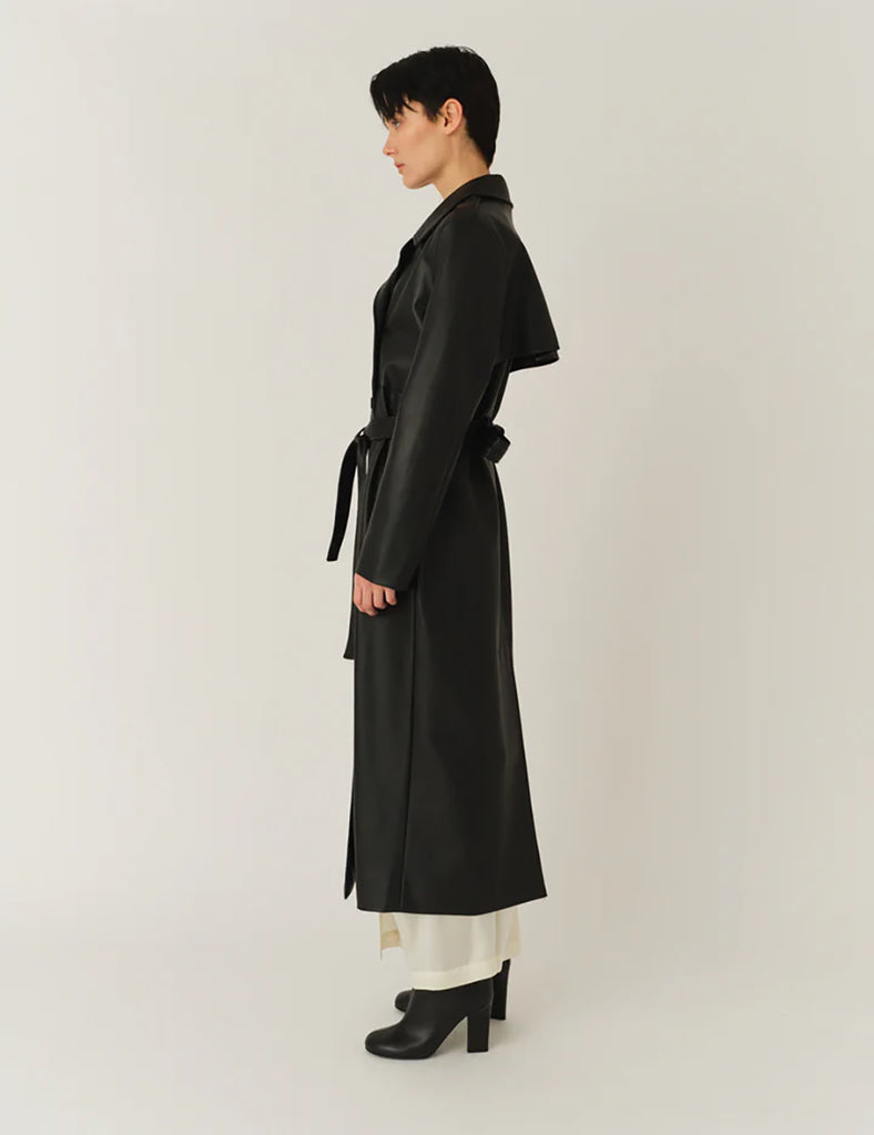 Długi, elegancki, dwurzędowy płaszcz Brooklyn Trench Black z klasycznymi detalami, wiązany w talii za pomocą wyciąganego, szerokiego paska. Posiada kołnierzyk, pagony na ramionach i luźne rękawy. Z tyłu u dołu ma rozcięcie. Płaszcz posiada dwie, boczne kieszenie. Jest zapinany na guziki. Wykończony w matowym, czarnym kolorze.