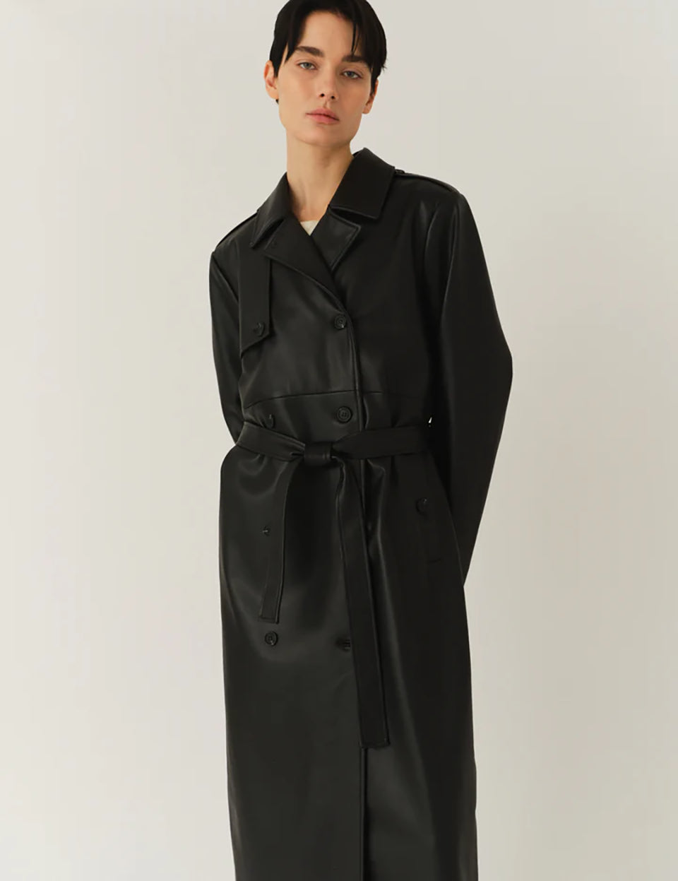 Długi, elegancki, dwurzędowy płaszcz Brooklyn Trench Black z klasycznymi detalami, wiązany w talii za pomocą wyciąganego, szerokiego paska. Posiada kołnierzyk, pagony na ramionach i luźne rękawy. Z tyłu u dołu ma rozcięcie. Płaszcz posiada dwie, boczne kieszenie. Jest zapinany na guziki. Wykończony w matowym, czarnym kolorze.