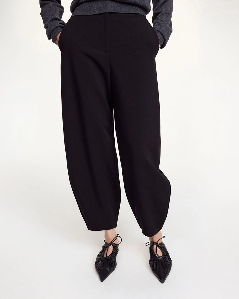 Klasyczne, garniturowe spodnie Carlien By Malene Birger z wysokim stanem i zaokrągloną, zwężaną u dołu nogawką w typie barrel cut. Spodnie posiadają dwie, boczne kieszenie i szlufki na pasek