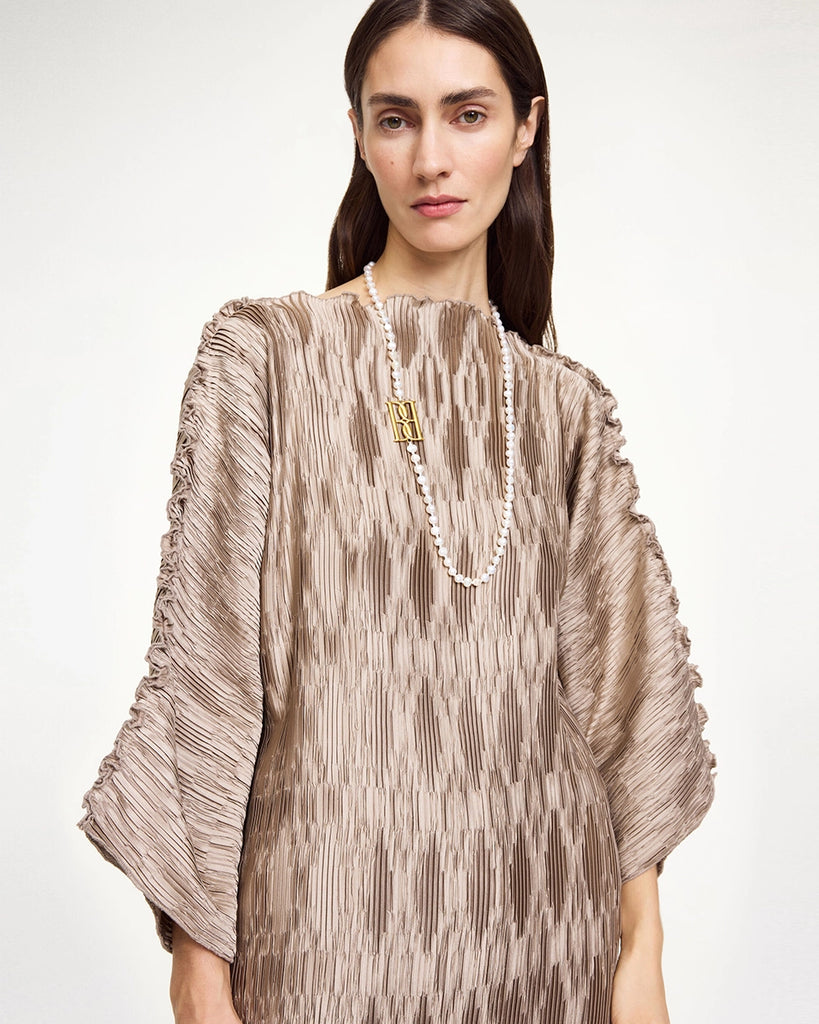 Elegancka, wieczorowa sukienka Tralaido By Malene Birger o oversizowym fasonie z prostym dekoltem i szerokimi rękawami 3/4. Sukienka ma dwa, boczne rozcięcia u dołu oraz wyciągany, cienki sznurek do zawiązania w pasie.