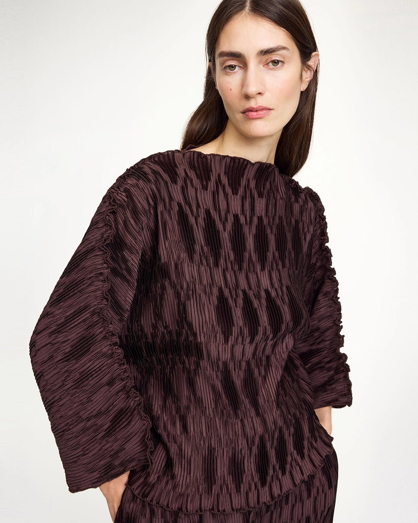 Elegancka bluzka Tralluman By Malene Birger z dekoltem w formie łódki i z szerokim rękawem 3/4. Posiada prosty krój i luźny fason. Wykonana z satynowej, plisowanej tkaniny