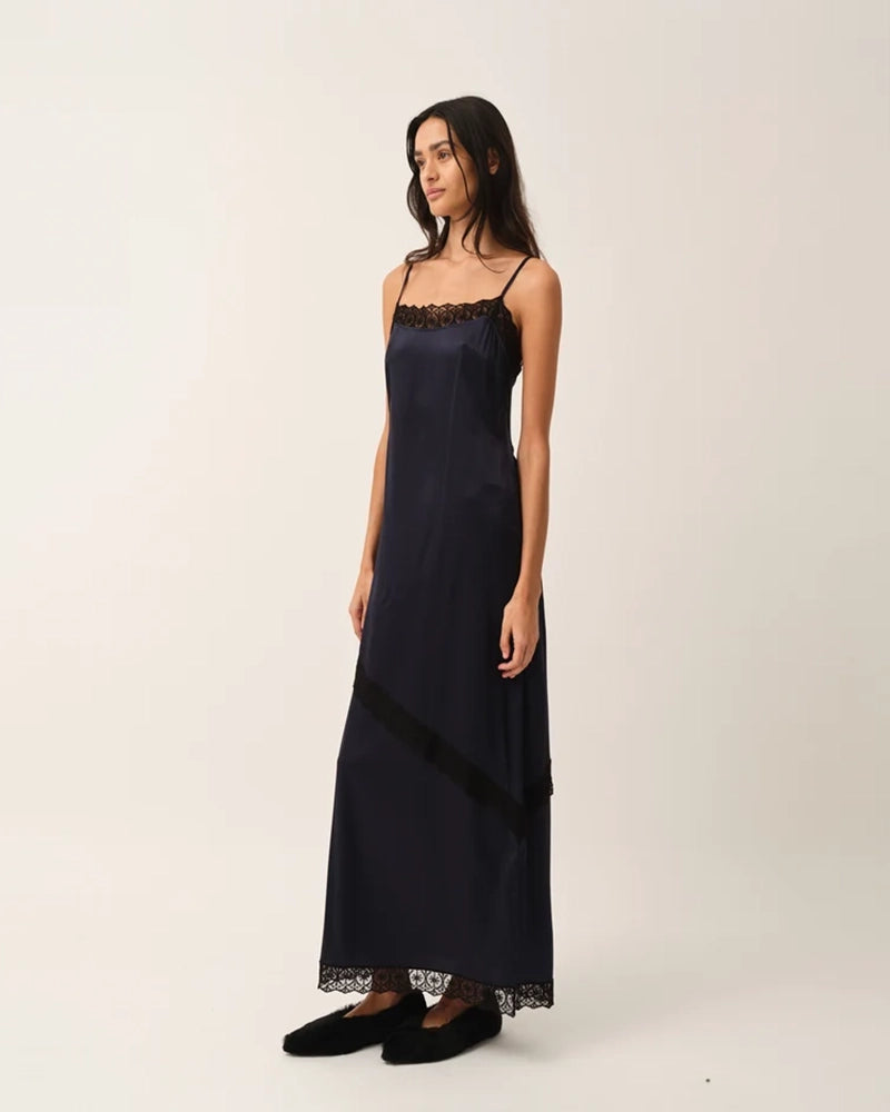 Elegancka, lejąca sukienka maxi na cienkich, regulowanych ramiączkach Cata Lace The Garment wykończona zmysłową koronką. Posiada prosty dekolt i głębokie wycięcie na plecach. Z przodu dekorowana asymetryczną koronką. Sukienka ma boczne rozcięcie oraz długość do kostek. Z tyłu delikatnie drapowana. Wykonana z jedwabnej, śliskiej tkaniny.