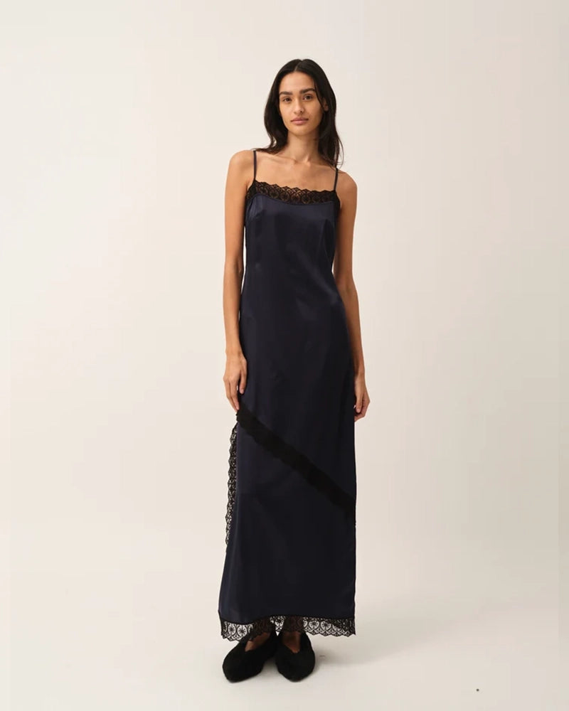 Elegancka, lejąca sukienka maxi na cienkich, regulowanych ramiączkach Cata Lace The Garment wykończona zmysłową koronką. Posiada prosty dekolt i głębokie wycięcie na plecach. Z przodu dekorowana asymetryczną koronką. Sukienka ma boczne rozcięcie oraz długość do kostek. Z tyłu delikatnie drapowana. Wykonana z jedwabnej, śliskiej tkaniny.