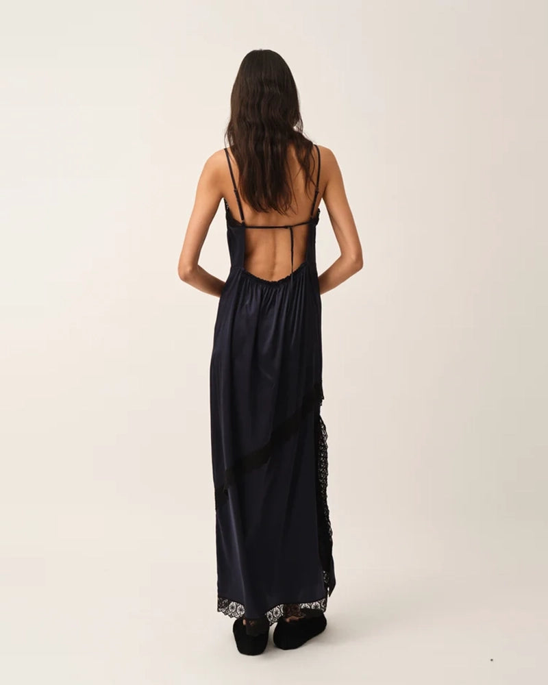 Elegancka, lejąca sukienka maxi na cienkich, regulowanych ramiączkach Cata Lace The Garment wykończona zmysłową koronką. Posiada prosty dekolt i głębokie wycięcie na plecach. Z przodu dekorowana asymetryczną koronką. Sukienka ma boczne rozcięcie oraz długość do kostek. Z tyłu delikatnie drapowana. Wykonana z jedwabnej, śliskiej tkaniny.