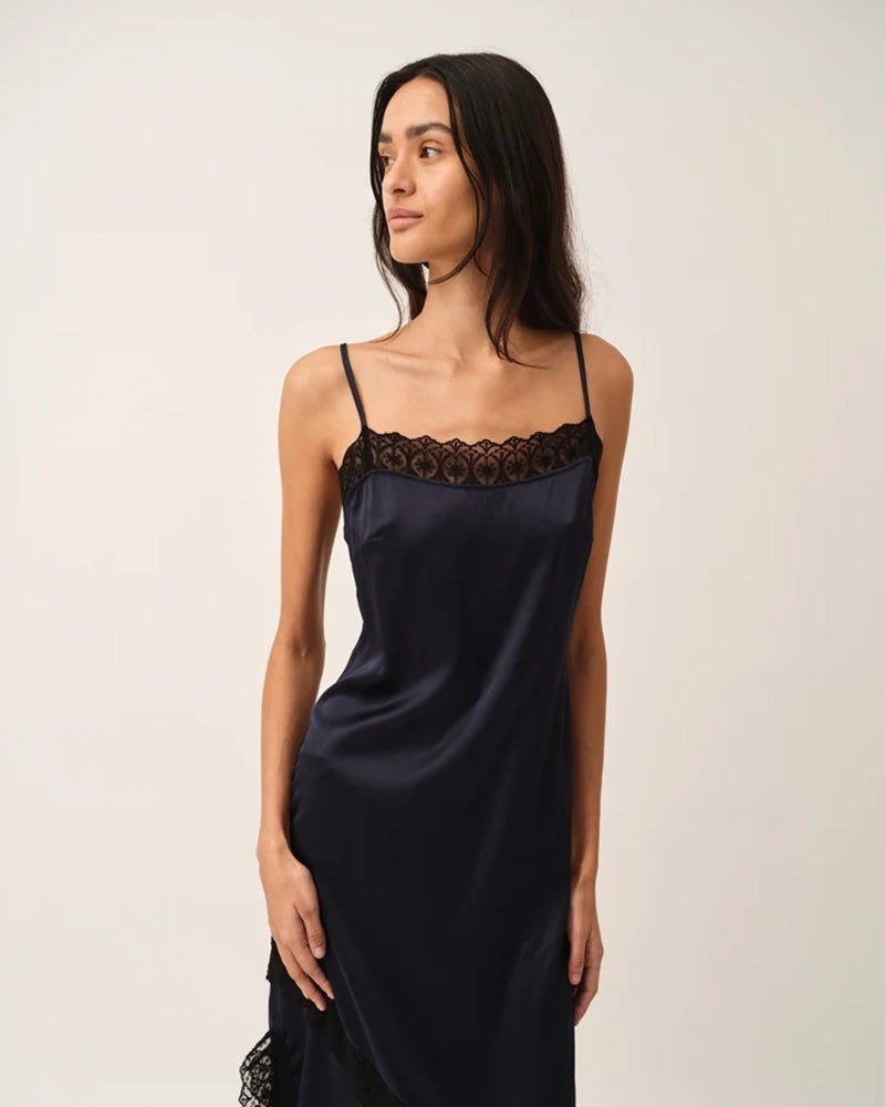 Elegancka, lejąca sukienka maxi na cienkich, regulowanych ramiączkach Cata Lace The Garment wykończona zmysłową koronką. Posiada prosty dekolt i głębokie wycięcie na plecach. Z przodu dekorowana asymetryczną koronką. Sukienka ma boczne rozcięcie oraz długość do kostek. Z tyłu delikatnie drapowana. Wykonana z jedwabnej, śliskiej tkaniny.