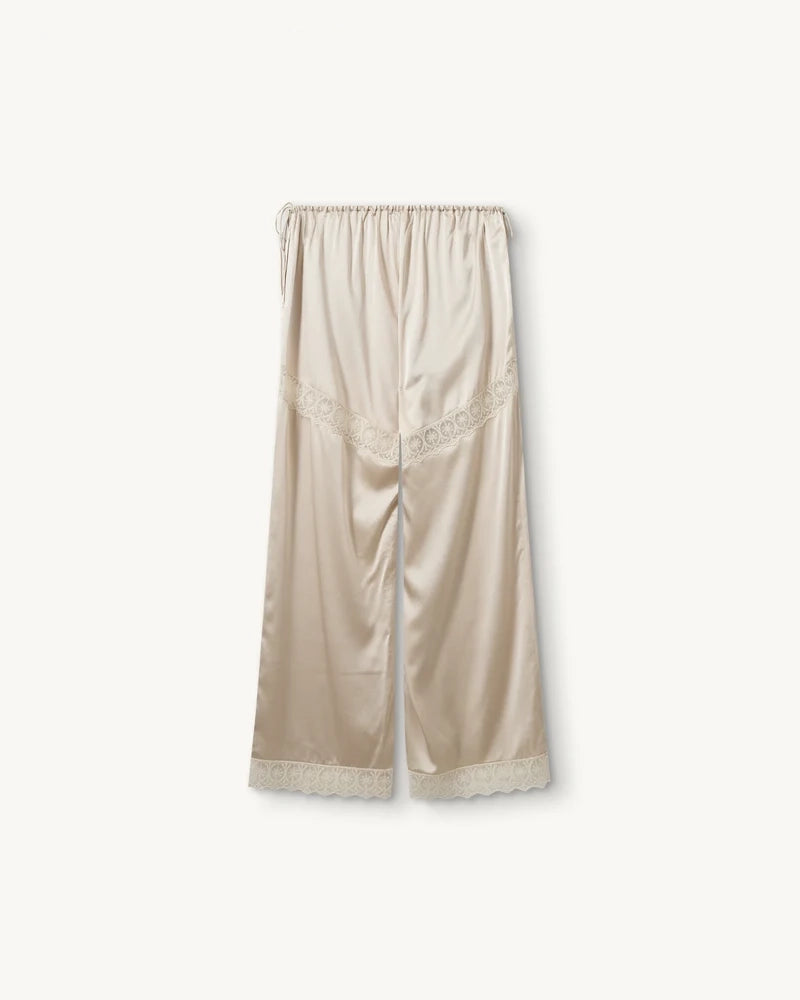 Lejące, jedwabne spodnie Cata Lace The Garment ze średnim stanem i prostą, luźną nogawką. Wiązane na bokach bioder. Wykończone zmysłową koronką. 