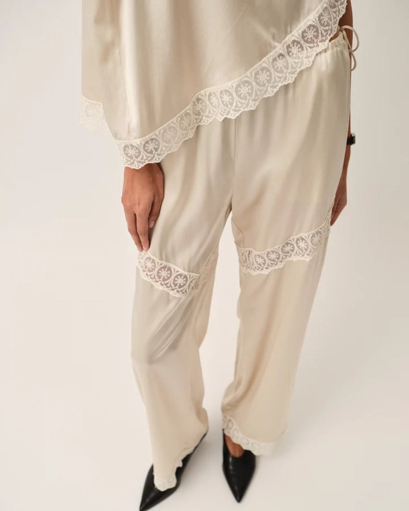 Lejące, jedwabne spodnie Cata Lace The Garment ze średnim stanem i prostą, luźną nogawką. Wiązane na bokach bioder. Wykończone zmysłową koronką. 