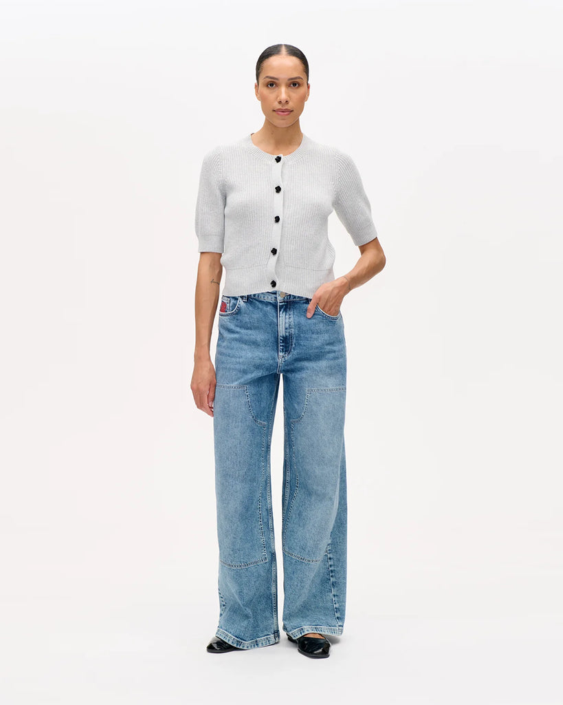 Dzianinowy, krótki kardigan Cathia Grey Melange z krótkim rękawem, o lekko dopasowanym kroju. Zapinany na zatrzaski zdobione błyszczącymi kwiatami. Wykonany z bawełny organicznej. Sweterek zestaw ze swoimi ulubionymi jeansami lub spódnicą.