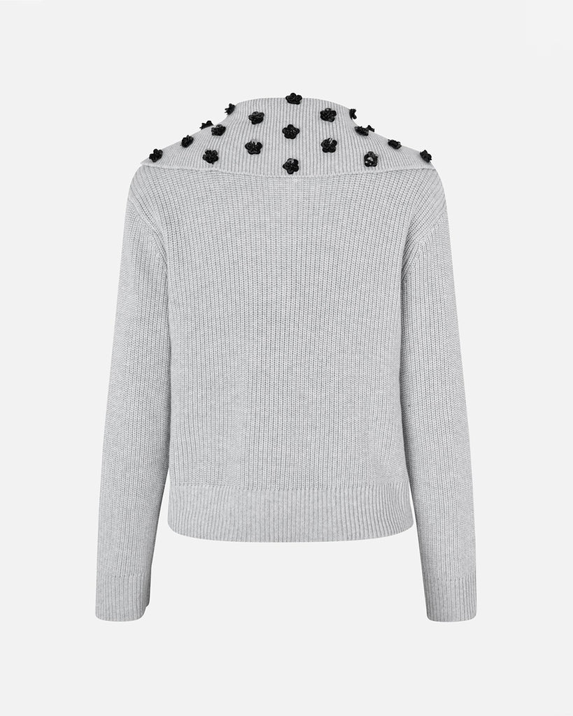 Luźny, bawełniany sweter Clare Grey Melange z obniżonymi ramionami i kołnierzykiem zapinanym na zatrzaski, który ozdobiony jest cekinowymi kwiatami. Posiada ściągacz u dołu. Noś go z ulubionymi jeansami, aby dodać uroku swojej codziennej stylizacji.