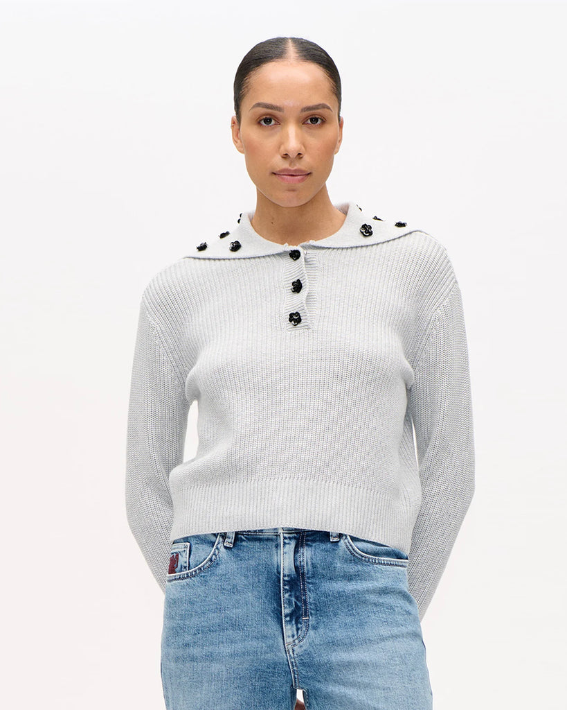 Luźny, bawełniany sweter Clare Grey Melange z obniżonymi ramionami i kołnierzykiem zapinanym na zatrzaski, który ozdobiony jest cekinowymi kwiatami. Posiada ściągacz u dołu. Noś go z ulubionymi jeansami, aby dodać uroku swojej codziennej stylizacji.