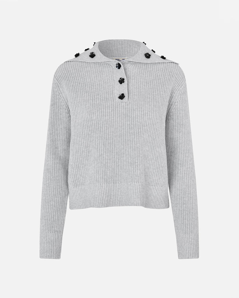 Luźny, bawełniany sweter Clare Grey Melange z obniżonymi ramionami i kołnierzykiem zapinanym na zatrzaski, który ozdobiony jest cekinowymi kwiatami. Posiada ściągacz u dołu. Noś go z ulubionymi jeansami, aby dodać uroku swojej codziennej stylizacji.