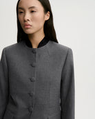 Dopasowana, jednorzędowa marynarka Claye By Malene Birger Dark Grey Melange w stylu vintage ze stójką. Zapinana na rząd drobnych, dyskretnych guzików. Fason charakteryzuje się mocno zaznaczoną, strukturalną linią ramion oraz zaokrąglonym dołem. U dołu po obu stronach umieszczono symetryczne kieszenie z klapkami, a dopasowane, proste rękawy dopełniają elegancki, formalny charakter. Posiada podszewkę i kieszeń wewnętrzną.&nbsp;

-Jednorzędowy fason

-Kontrastowa stójka

-Dopasowany krój